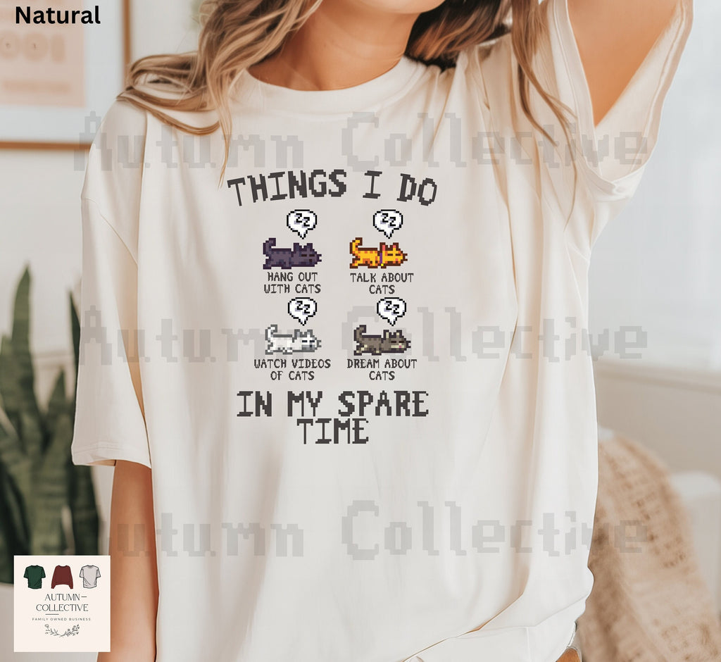 Original Things I do in my spare time Stardew Valley Shirt. Four sleeping cats in the colors black, orange/yellow, white, and grey - captions underneath each cat; Hang out with cats, talk about cats, watch videos about cats, and dream about cats.